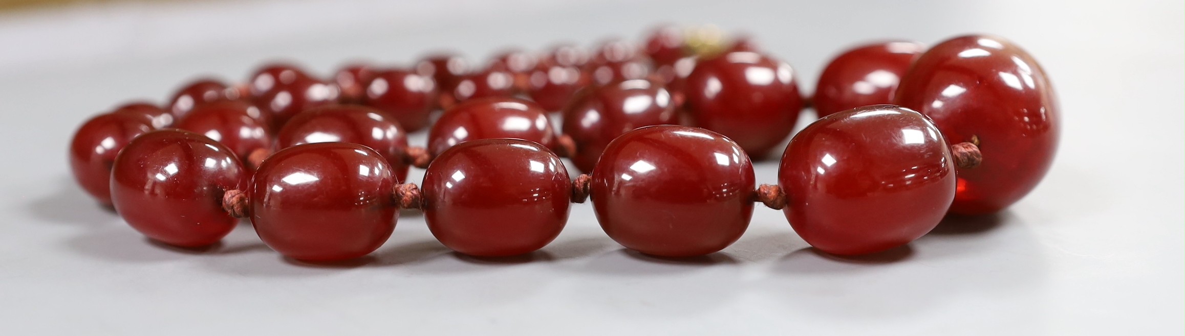 A single strand graduated oval simulated cherry amber bead necklace, 56cm, gross weight 75 grams.